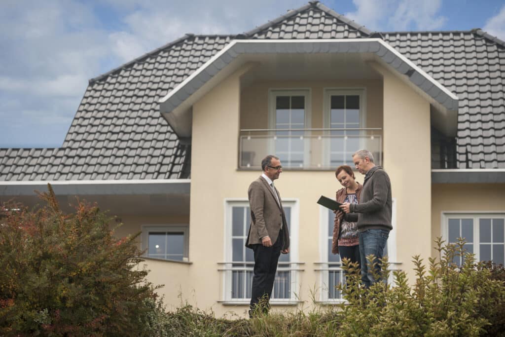 estate agent with potential buyers in front of residential house estate agent with potential buyers in front of residential house